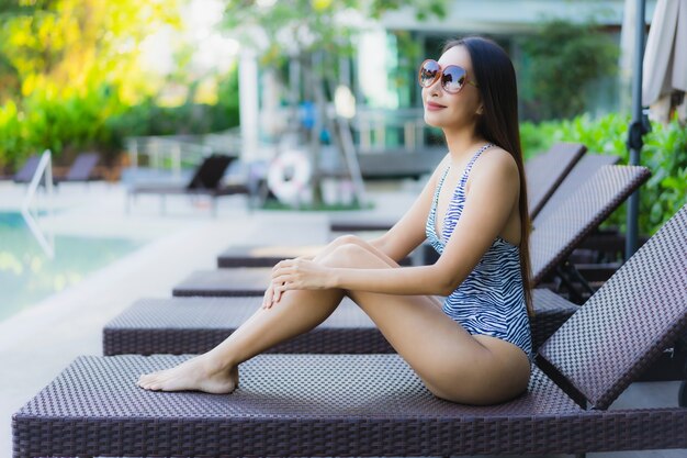 Beautiful young asian women happy smile relax around outdoor swimming pool in hotel resort