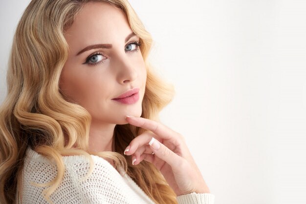 Beautiful young blonde Caucasian woman with wavy hair looking over her shoulder