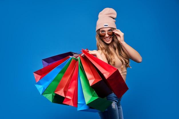 Beautiful young blonde woman in sunglasses and a hat with packages on sale