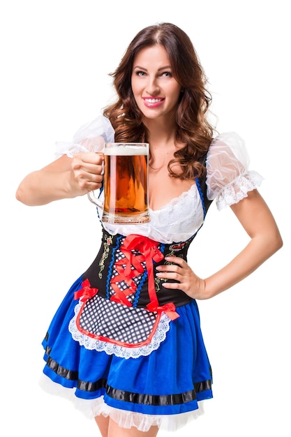 Beautiful young brunette girl in dirndl drinks out of oktoberfest beer stein. Isolated on white background.