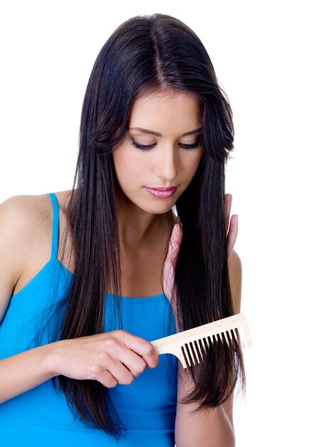 Beautiful young brunette woman combing her long luxury straight hair - isolated