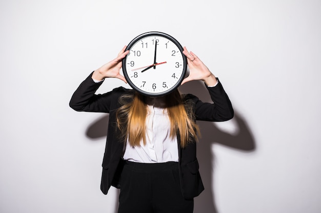 Beautiful young business woman holding clock in front of face on white