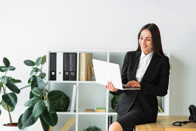 Foto gratuita bella giovane imprenditrice guardando portatile in ufficio