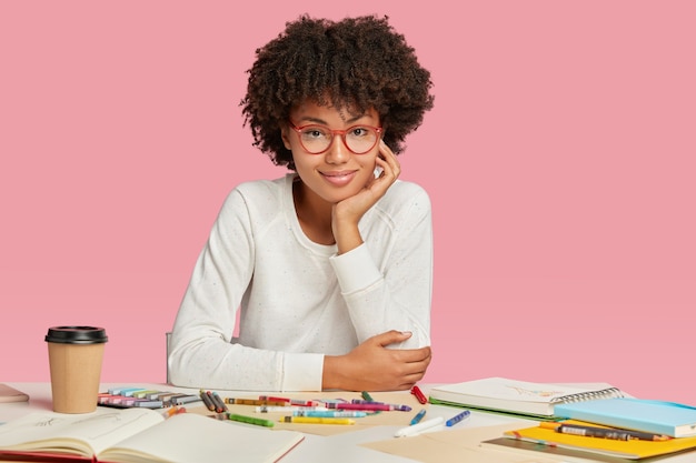 Beautiful young cartoonist or animator wears eyewear, white casual sweater involved in creative working process