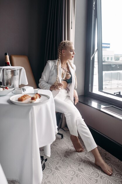 Beautiful young caucasian female with long blonde hair, nice face, bright earrings in white suit
