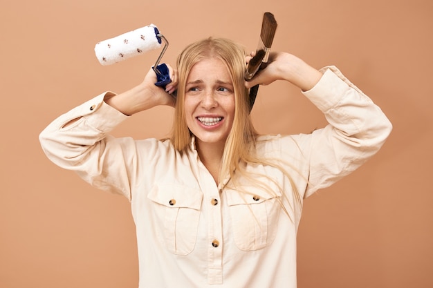 Foto gratuita bello giovane modello caucasico in pantaloncini colorati e camicia bianca e in posa tenendo il bilanciere nelle sue mani