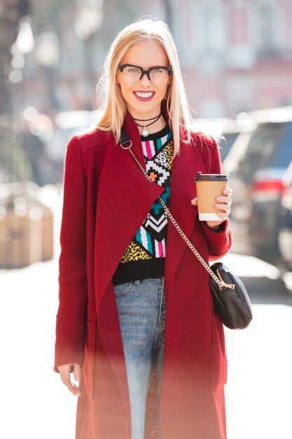 Beautiful young caucasian woman walking outdoors drinking coffee.