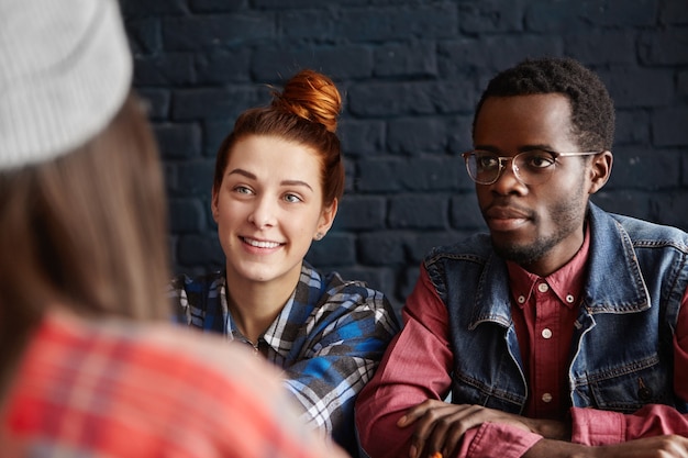 Free photo beautiful young caucasian woman with cheerful smile and african male hipster wearing spectacles