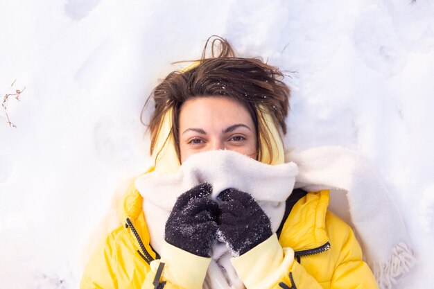 雪景色の冬の森の美しい若い陽気な女性は、冬に喜び、暖かい服を着て雪を楽しんでいます