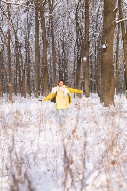 재미 눈 덮인 풍경 겨울 숲에서 아름 다운 젊은 쾌활 한 여자는 따뜻한 옷에 겨울과 눈에 기뻐