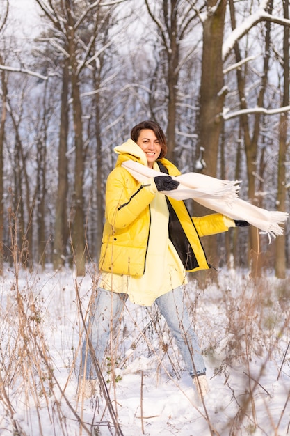 Beautiful young cheerful woman in a snowy landscape winter forest having fun rejoices in winter and snow in warm clothes