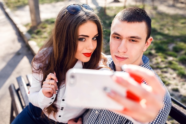 Beautiful young couple having fun on a bench in the park