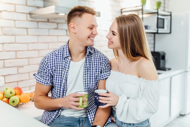 Beautiful young couple hugging while having breakfast together with coffee.