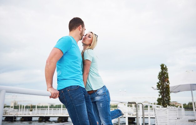 Beautiful young couple kissing on a pier near water.