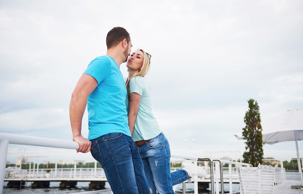 水の近くの桟橋でキス美しい若いカップル。