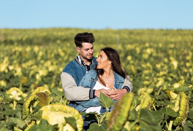 Beautiful young couple in love standing in a field of sunflowers.