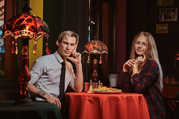 Beautiful young couple ordered nachos during dating at mexican restaurant.