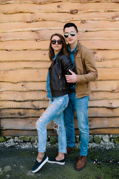 Красивая молодая пара позирует над деревянной стеной