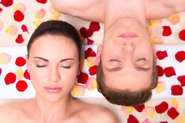 Beautiful young couple relaxes lying in rose petals.