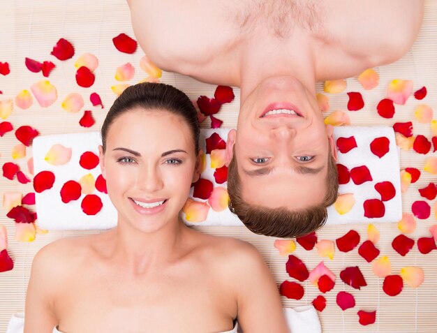 Beautiful young couple relaxes lying in rose petals.