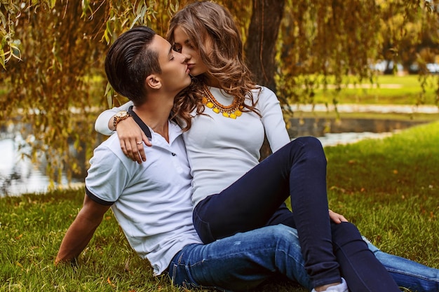 Beautiful young couple relaxing on grass field in a park.