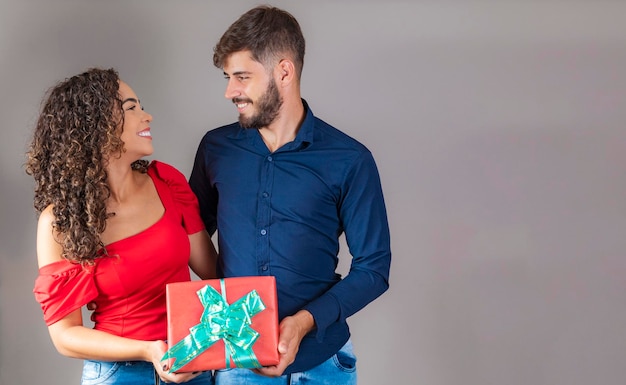 Beautiful young couple romantic woman delivers a holiday gift to her boyfriend gift concept for birthdays christmas valentine's day and men's day Premium Photo