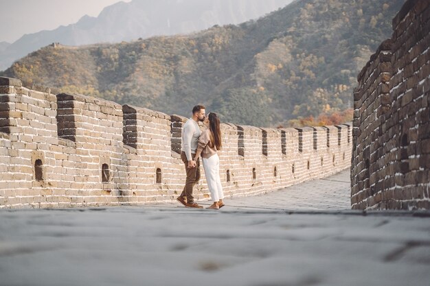 Beautiful young couple running and jumping at the Great Wall of China.