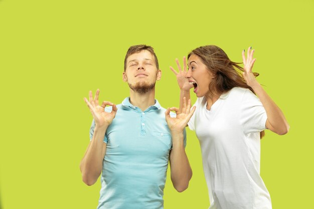 Beautiful young couple's half-length portrait isolated. Man is trying to keep calm with closed eyes while woman is screaming. Facial expression, human emotions concept.
