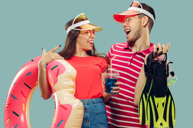 Beautiful young couple's half-length portrait isolated. Smiling woman and man in caps and sunglasses with swimming equipment. Facial expression, summer, weekend concept.