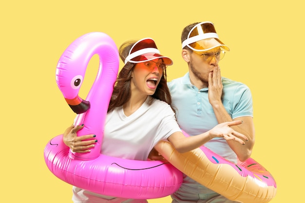 아름 다운 젊은 부부의 절반 길이 초상화 절연. 여자와 남자 모자와 선글라스 수영 반지와 함께 서. 표정, 여름, 주말 개념.