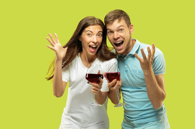 Beautiful young couple's half-length portrait isolated. Woman and man with glasses of red wine making selfie. Facial expression, summer, weekend concept. Trendy colors.