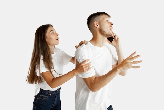 Beautiful young couple's portrait isolated on white studio wall