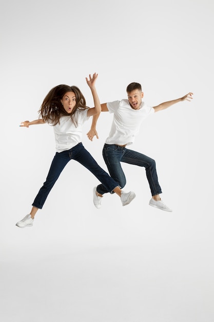 Free photo beautiful young couple's portrait isolated on white wall. facial expression, human emotions, advertising concept. copyspace. woman and man jumping, dancing or running together.