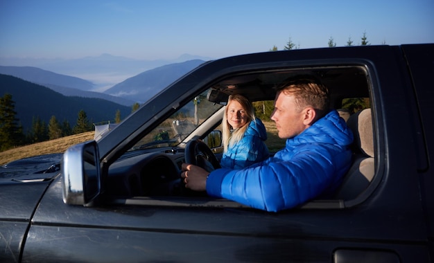 Beautiful young couple travelling in the car in mountains