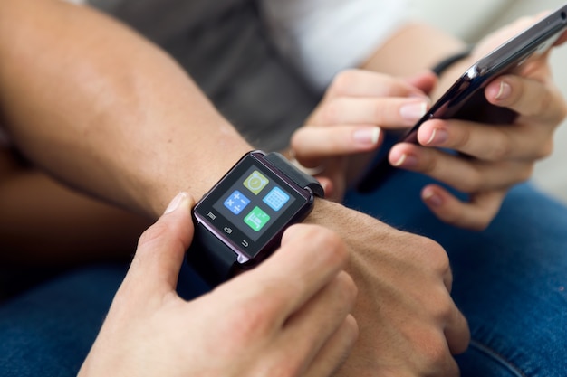 Beautiful young couple using a smartwatch at home.