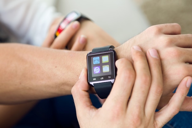 Beautiful young couple using a smartwatch at home.