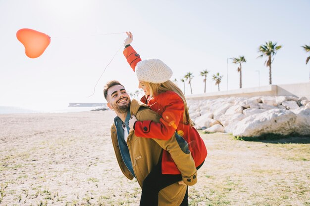 Beautiful young couple with balloon on shore