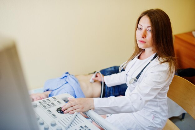 Beautiful young doctor doing diagnostic sonography on a patient