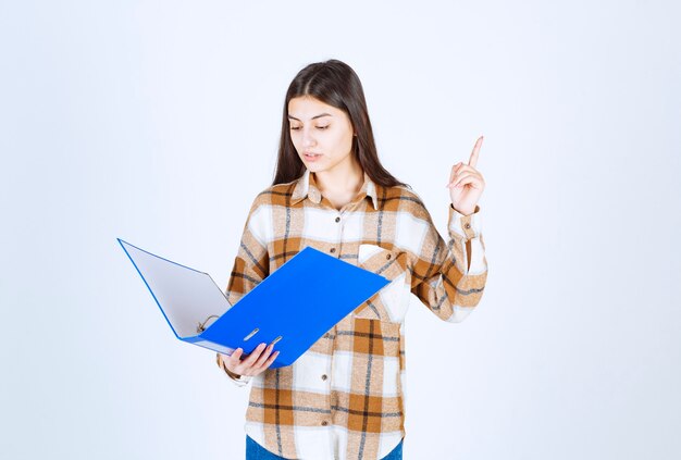 Beautiful young employee looking at documents inside of blue folder. 