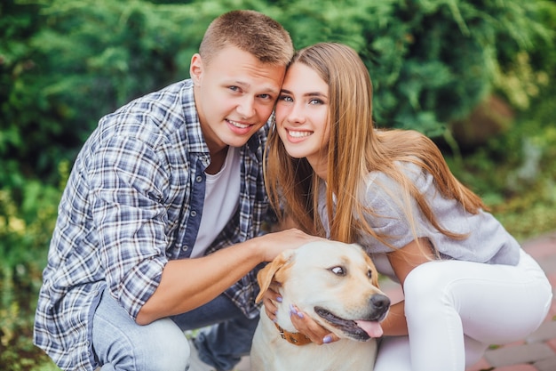 Foto gratuita bella giovane famiglia che gioca con il cane e sorride davanti