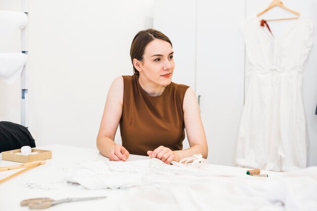 Beautiful young fashion designer with dress on workdesk