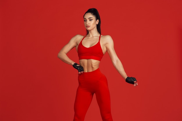 Beautiful young female athlete practicing on red wall monochrome portrait