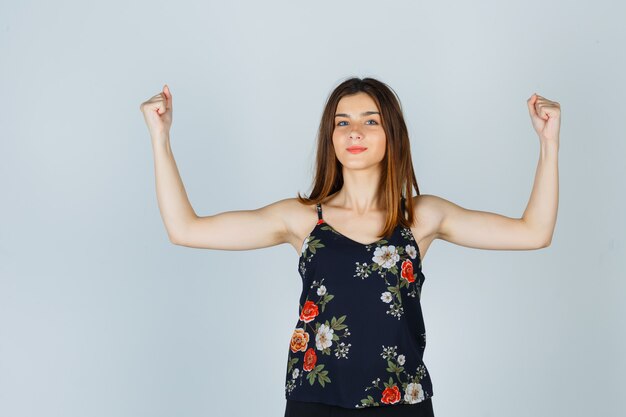 Free photo beautiful young female in blouse showing winner gesture and looking lucky