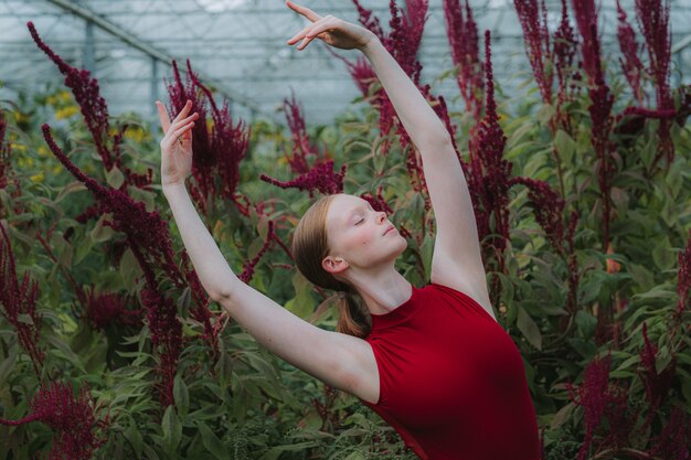 Beautiful young female dancer dancing in a botanical garden with amaranth plants