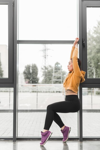 Beautiful young female dancer posing in front of window