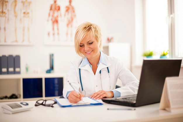 Beautiful young female doctor working at her office