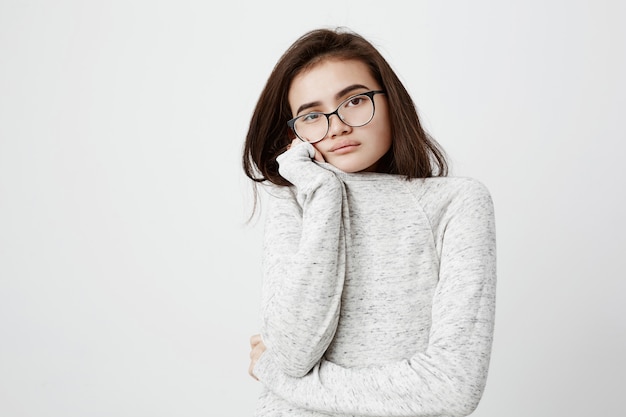 Beautiful young female model with dark straight hair, wearing long-sleeved t-shirt and eyeglasses, looking