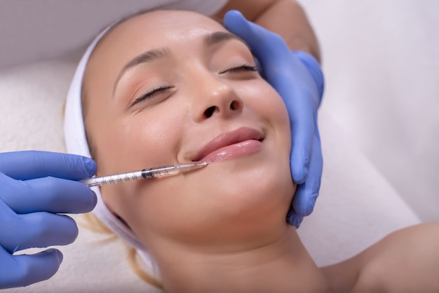 Красивая молодая женщина во время лечения кожи гиалуроновой кислотой в клинике красоты