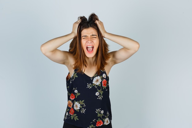 Beautiful young female snarling at camera while tearing at hair