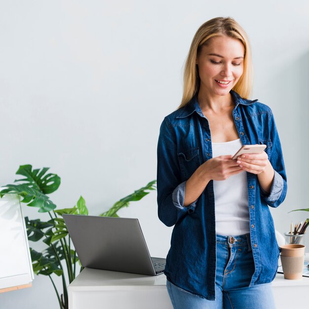 Beautiful young female using smartphone in office